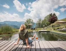Naturhotel Landhof Irschen Eine Dame sitzt am Schwimmteich des Naturhotels Landhof Irschen